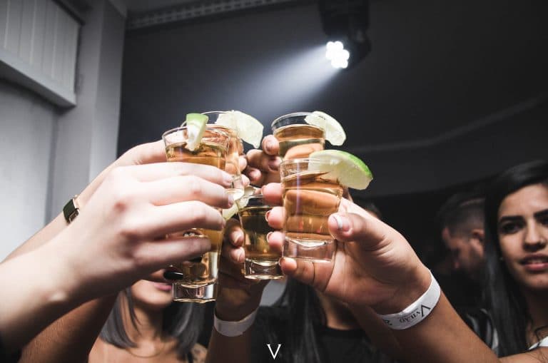Group of people raising shot glasses in a cheers
